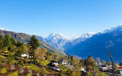 Himalayan village with snow-capped mountains in the background under a blue sky